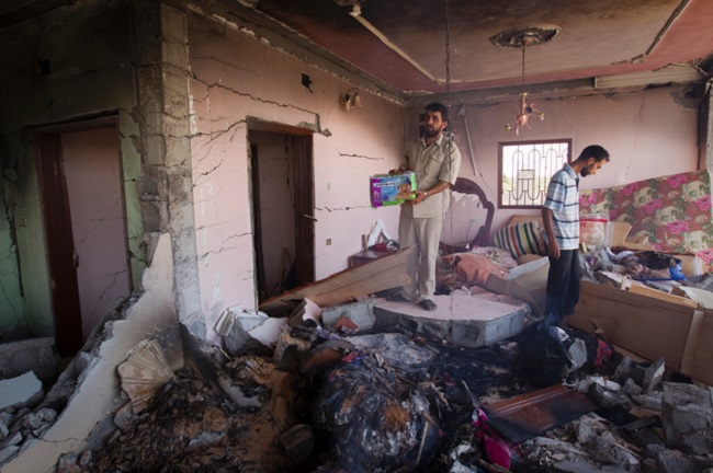 A man holds a pack of diapers found in the rubble of a house Libyan officials say was bombed by NATO forces in Majar, a village south of Zlitan, 160km (99 miles) east of Tripoli, Aug. 9, 2011.