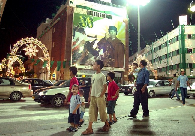 Aug 2005: Children walk past a poster of Libyan leader Moammar Gadhafi, as Libya prepares to celebrate the 36th anniversary of the Libyan Revolution, which overthrew the monarchy in Tripoli.