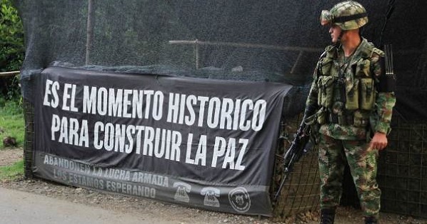 A Colombian soldier stands at an army checkpoint next to a sign saying “This is a historic moment to build peace