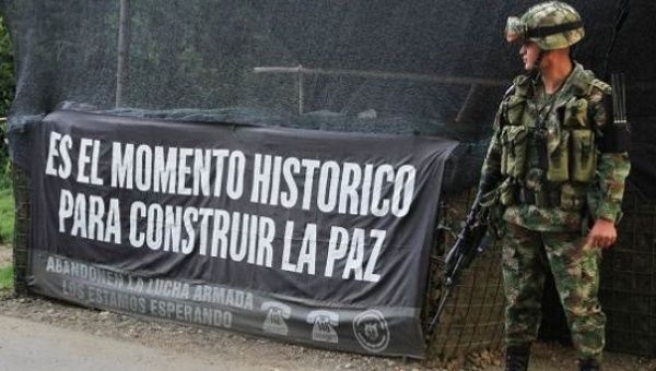 A Colombian soldier stands at an army checkpoint next to a sign saying “This is a historic moment to build peace