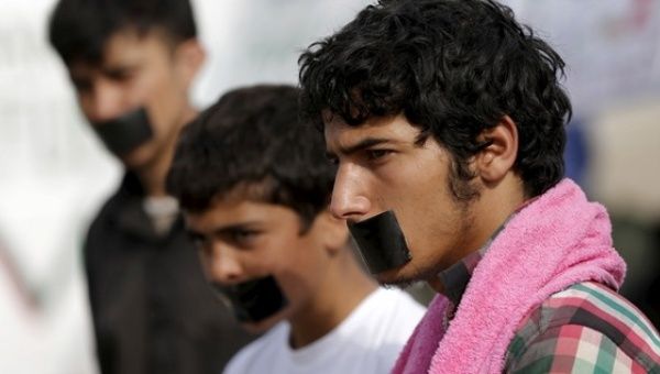 Refugees with their mouths taped stage a protest at a makeshift camp at the Greek-Macedonian border near the village of Idomeni, Greece, April 1, 2016.