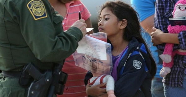 A young undocumented Salvadoran immigrant watches as a U.S. Border Patrol agent records family information.