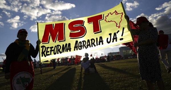 MST activists hold a sign in Brasilia demanding 