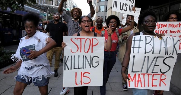 Protesters hold signs against police killings of Black people.