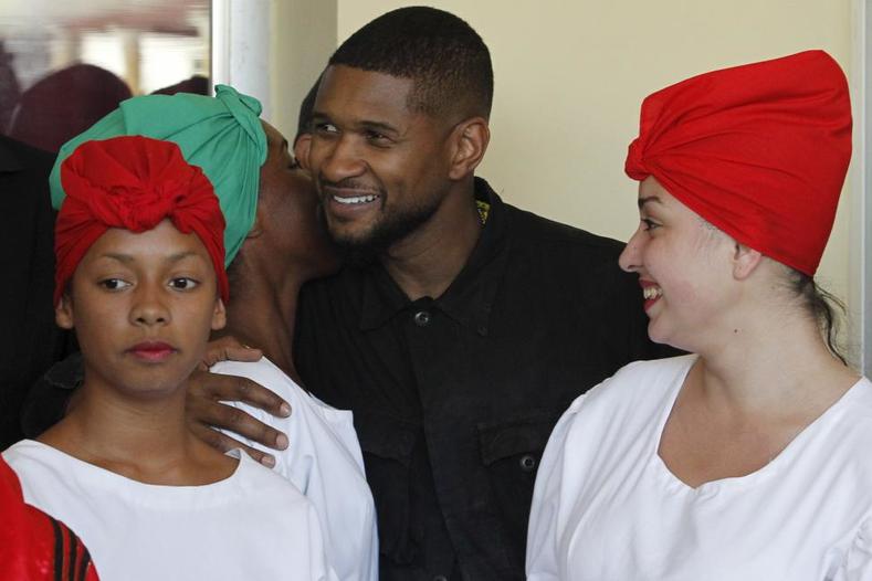 Singer Usher Raymond (C), a member of a delegation representing U.S. President Barack Obama's arts and humanities committee, stands between students during a visit at the Superior Institute of Arts in Havana, Cuba, April 18, 2016.