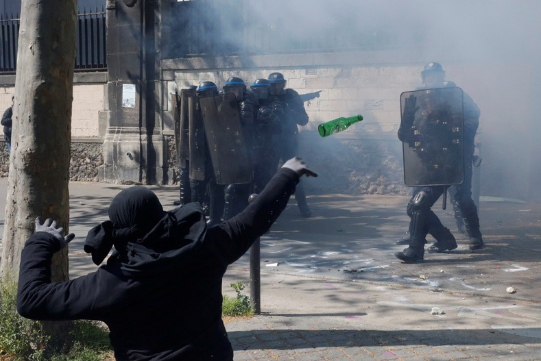 A hooded youth throws a bottle during a clash with French riot police to protest against the French labour law proposal during the May Day labour union march in Paris, France, May 1, 2016.