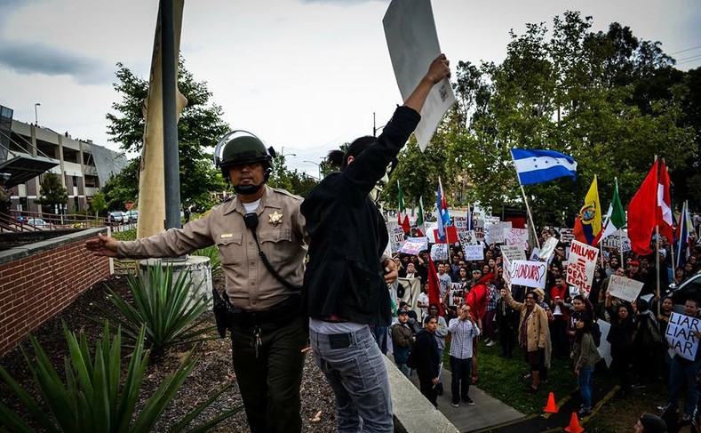 An officer of the Los Angeles County Sheriff's Department shoves a protester aside at the May 5, 2016 protest at East LA College.