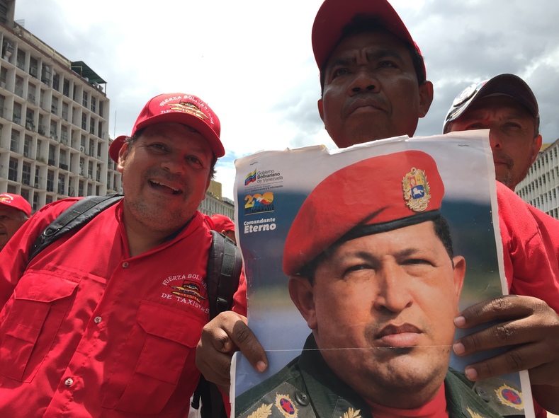 Freddie Layer (R) watches intently as he holds a photo of late President Hugo Chavez, while Alexi Morales (L) poses for the photo 
