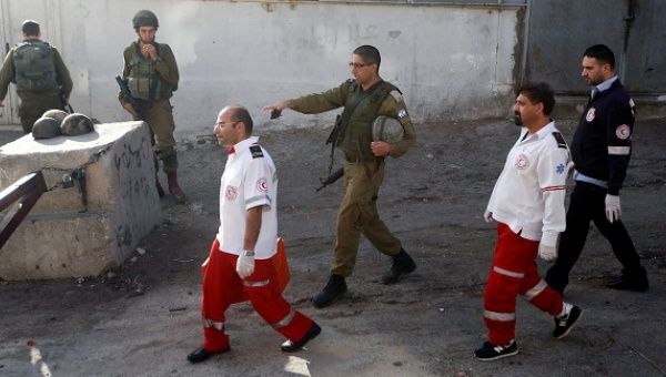Israeli forces and Palestinian medics walk near the scene of what the Israeli military said was a stabbing attack by a Palestinian, in Tal-Rumida in the West Bank city of Hebron September 17, 2016.