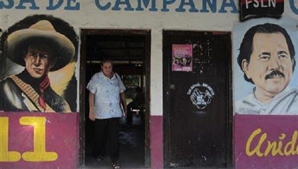 A woman walks past murals of Nicaragua's President Daniel Ortega (R)