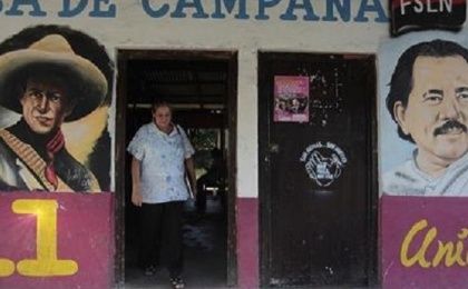 A woman walks past murals of Nicaragua's President Daniel Ortega (R)