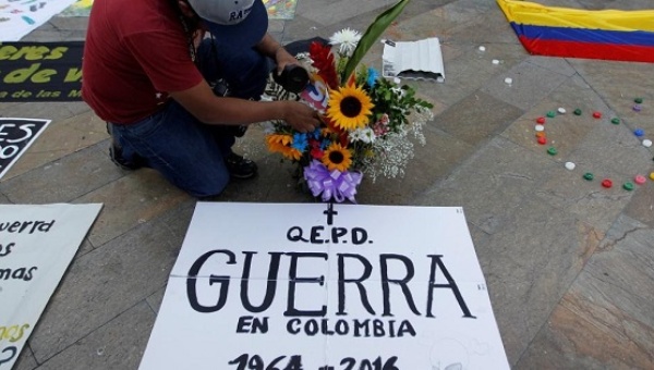 A man celebrates the signing of a cease-fire deal between the Colombian government and FARC. The sign reads 