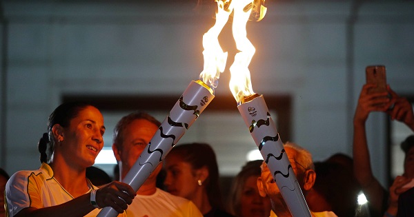 One athlete relays the Olympic torch to another in the streets of Sao Jose dos Campos