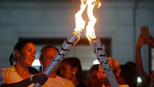One athlete relays the Olympic torch to another in the streets of Sao Jose dos Campos