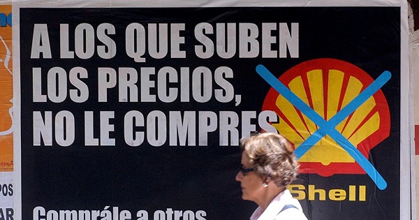 A woman walks past a sign against price hikes by Shell in Argentina