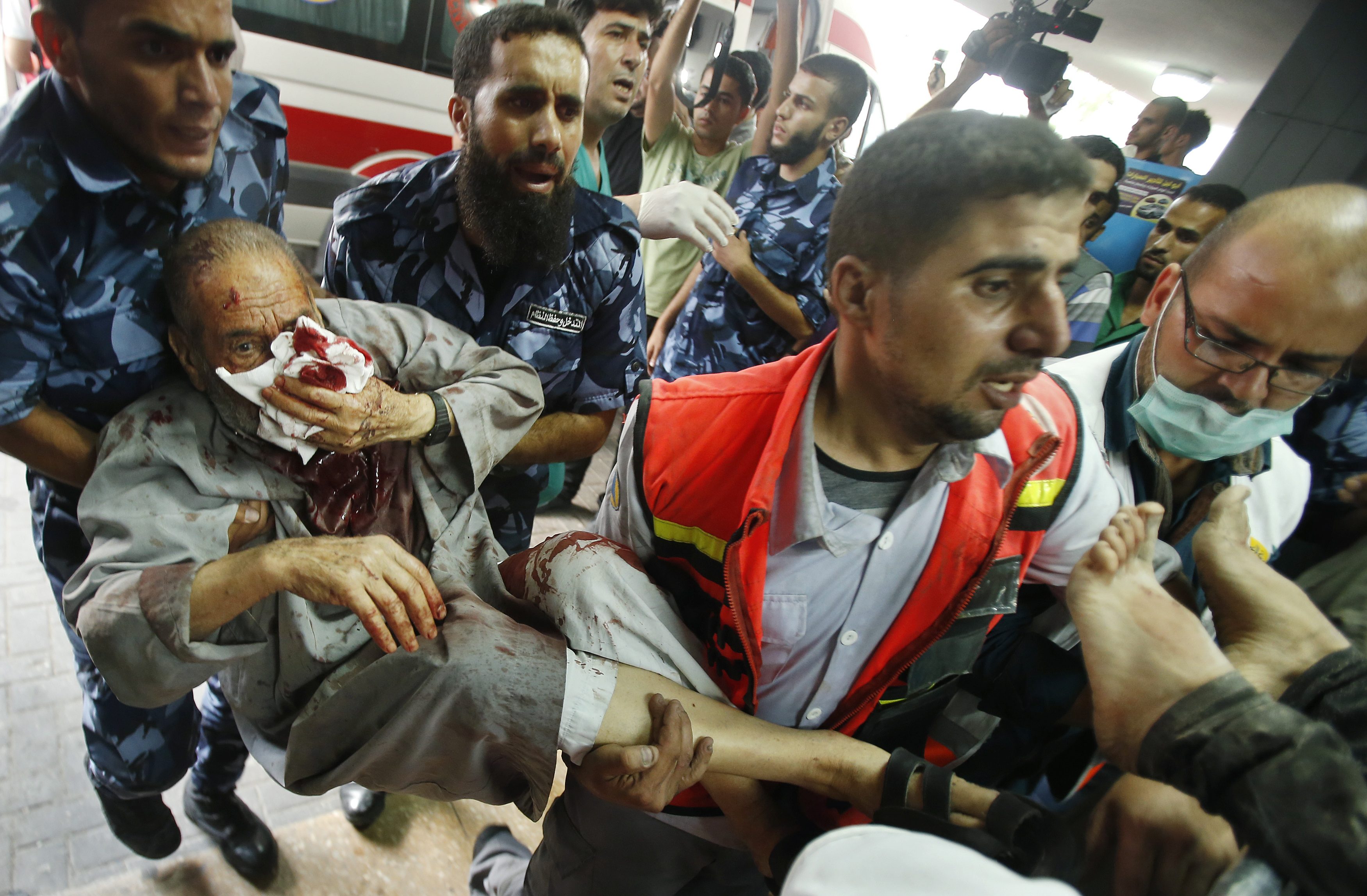 Palestinian policemen and medics carry a man, who medics said was wounded in Israeli shelling, at a hospital in Gaza City July 20, 2014.