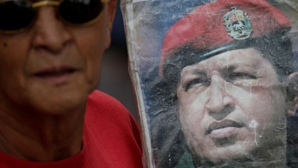 A supporter of holds an image of Venezuela's late President Hugo Chavez during a gathering in Caracas, Venezuela October 1, 2016.
