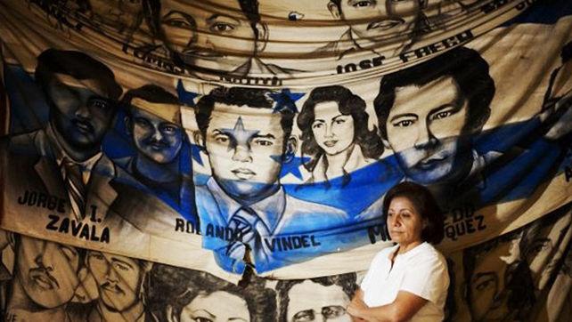 Bertha Oliva, founder and director of COFADEH whose husband was disappeared by Battalion 316, stand in front of a banner of the disappeared.