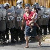 A woman and her daughter walk past a riot police officers in Managua City, Nicaragua.