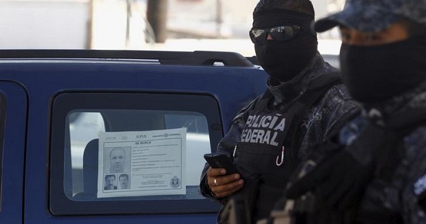 Federal police officers stand guard near a vehicle with a ''Wanted'' sign of fugitive kingpin Joaquin ''El Chapo'' Guzman glued to the window at the site of a passageway Mexican authorities on Thursday attributed to the cartel of Guzman, in Tijuana, October 24, 2015.