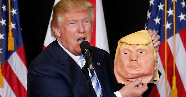 Republican presidential nominee Donald Trump holds up a mask of himself as he speaks during a campaign rally in Sarasota, Florida.