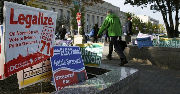 Pedestrians pass by a Washington, D.C., cannabis campaign sign, Nov. 4, 2014.