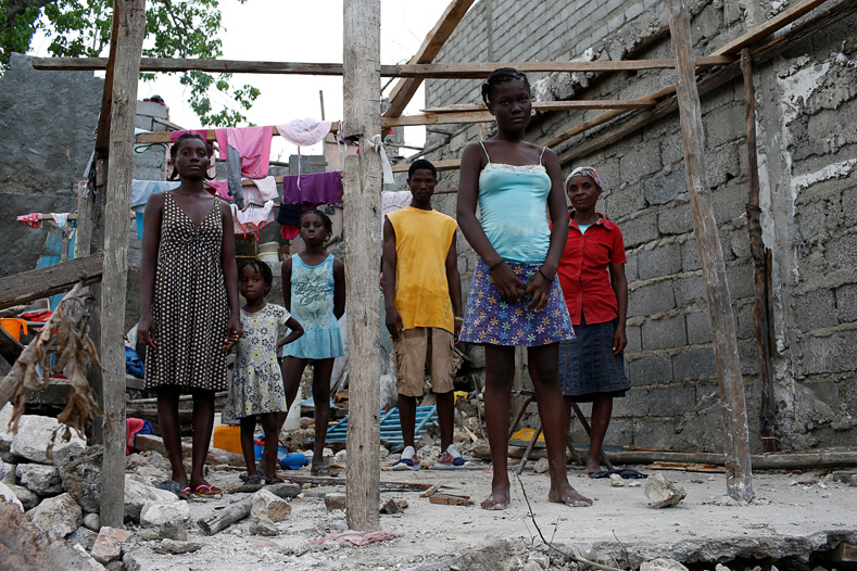 Roseline Charles (R), 57, poses for a photograph next to her relatives in their destroyed house after Hurricane Matthew hit Jeremie, Haiti, October 15, 2016. 