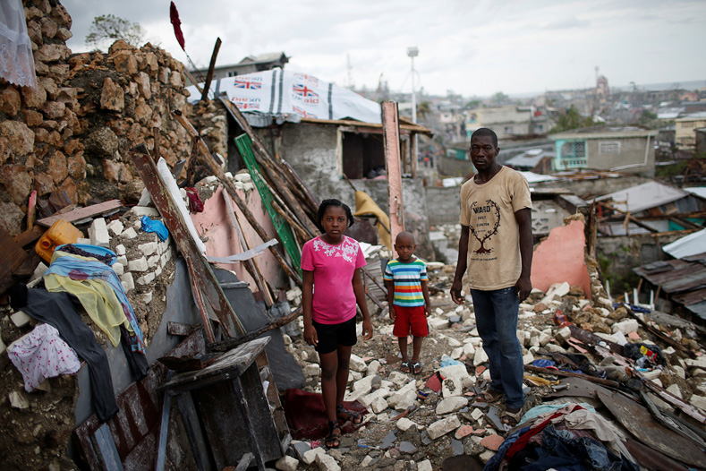 Eric Dominique (R), 26, poses for a photograph with his wife Mickerlange Pierre, 25, and their one-year-old son Jevens, in front of their partially rebuilt house after Hurricane Matthew hit Jeremie, Haiti, October 20, 2016. 