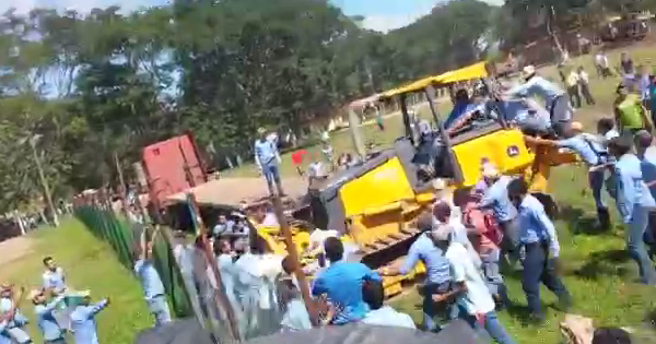 A bulldozer is forcing the entrance of the campus occupied by students, sweeping away the fence as well as protesters.