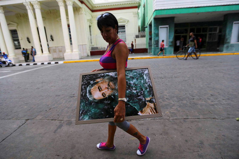 A woman carries a portrait of Cuba's late President Fidel Castro in Santa Clara, Cuba, Nov. 30, 2016. 