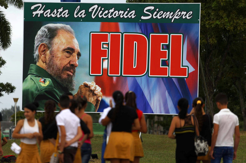 People stand in front of a billboard to Cuba's late President Fidel Castro in Santa Clara, Cuba, Nov. 30, 2016. 