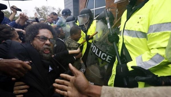 Activist Cornel West pushes against police officers during a protest at the Police Department in Ferguson.