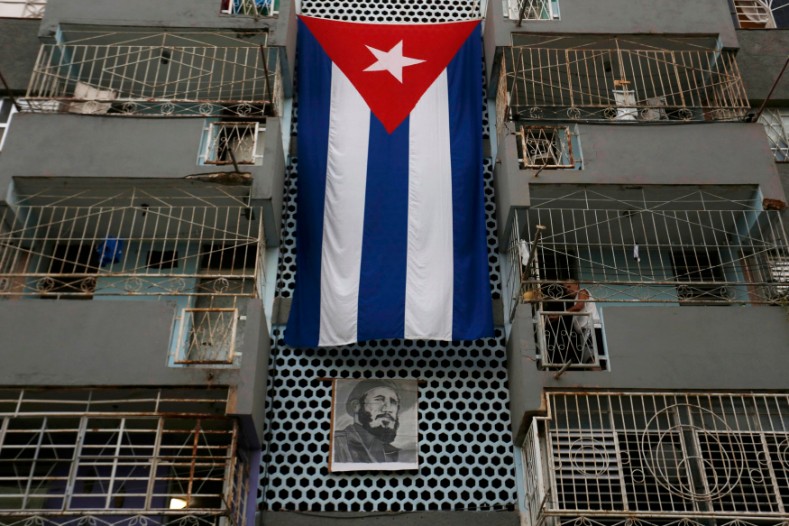 An apartment building is decorated with the national flag and a photograph of former President Fidel Castro as a man stands on his balcony in Havana, Dec. 3, 2016. 