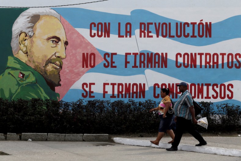People walk past graffiti of Cuba's late president Fidel Castro in Santiago de Cuba, which reads: 