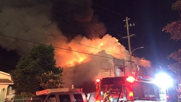 Flames rise from the top of a warehouse, which caught fire during a dance party in Oakland, California.