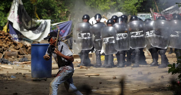 An injured protester flees as riot police use tear gas and batons to disperse a protest against the Tambor mine, Guatemala, May 23, 2014.