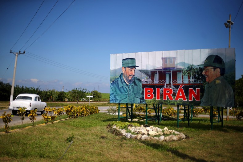A car drives past a sign showing photographs of Cuba's former President Fidel Castro and his brother, Cuba's President Raul Castro, in Biran.