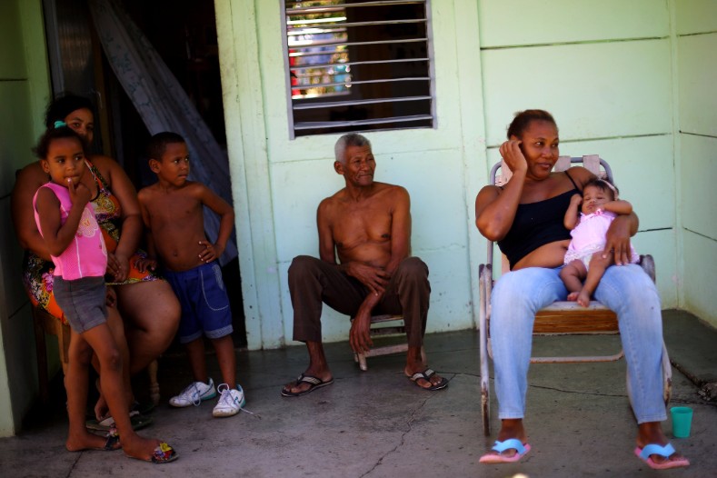 A family sits outside their home near the estate where Cuba's former President Fidel Castro was born, in Biran.