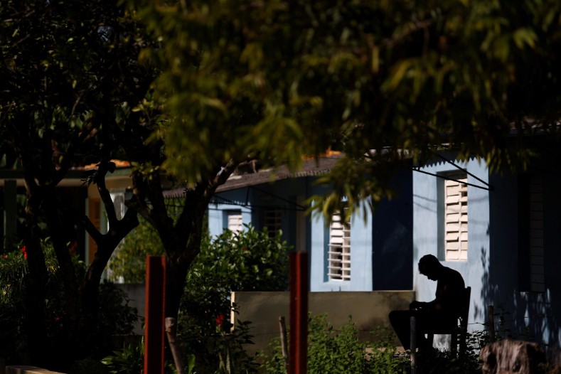 A man sits outside a house near the birthplace of Cuba's former President Fidel Castro in Biran.