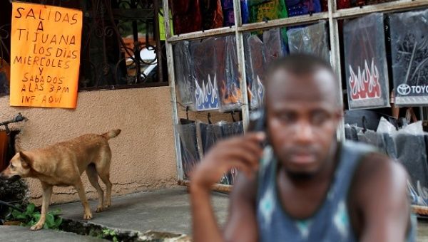 A placard is seen behind a Haitian migrant talking on a mobile in Tapachula, Chiapas, Mexico, Nov. 16, 2016.