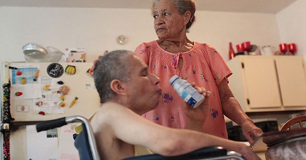 A woman is seen taking care of her son, who can’t feed or dress himself after a series of seizures, at their home in San Juan, Puerto Rico.