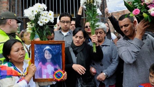 Relatives hold pictures of the 7-year-old Yuliana Samboni and flowers, in Colombia.