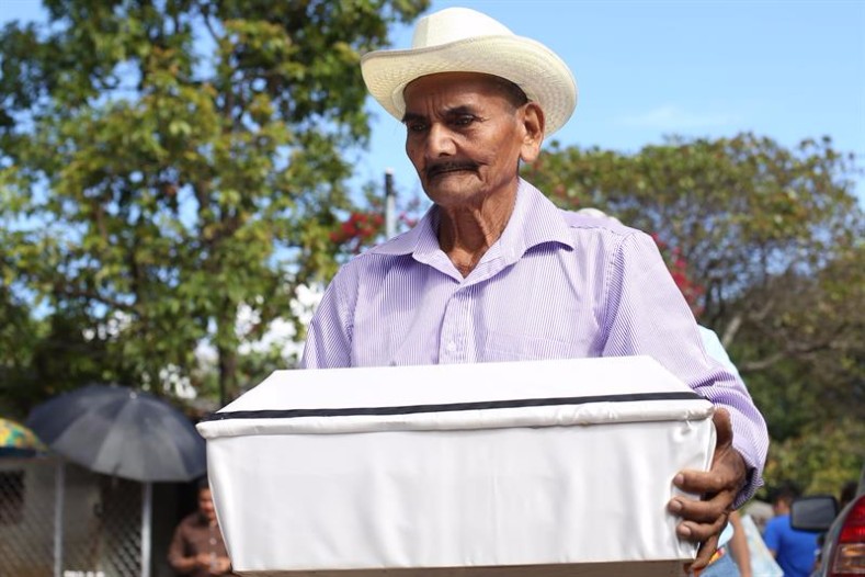 Angel Ramirez carries a coffin with the remains of one of his children, one of the hundreds of victims of the El Mozote massacre.