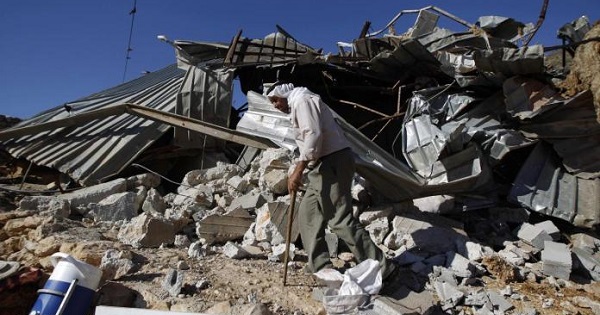 A Palestinian man walks past a structure after it was demolished by Israeli bulldozers in Khirbet Al-Taweel village near the West Bank City of Nablus.
