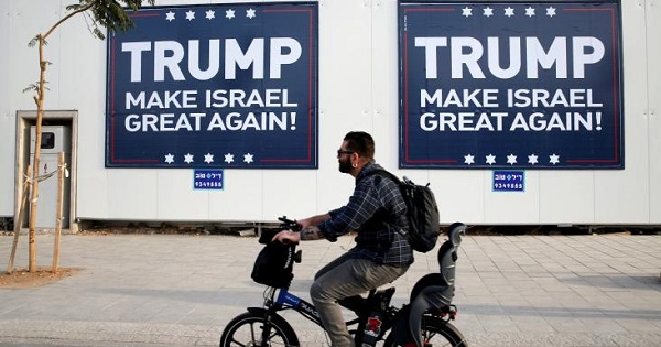 People walk past signs bearing the name of U.S. President-elect Republican Donald Trump in Tel Aviv, Israel Nov. 14, 2016.