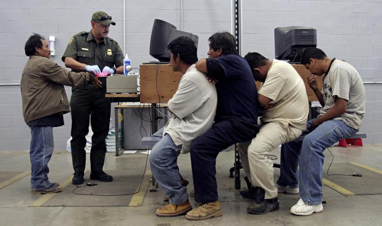 A man has his fingerprints electronically scanned by a U.S. Border Patrol agent while others wait for their turn at the US Border Patrol detention center in Nogales Arizona May 31 2006. The Barack Obama administration has cracked down on immigrants, deporting almost 3 million people back to conflict-ridden countries in Central and South America.