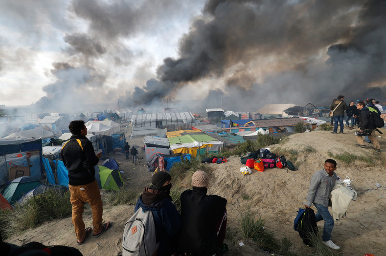 Fires blaze in October 2016 as authorities evacuate and bulldoze the refugee camp, known as the Jungle in Calais, France. After the evacuation, human rights organizations claimed one in three children had gone missing, possibly kidnapped by sex traffickers.