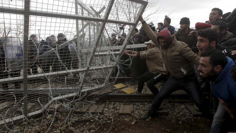 Stranded refugees and migrants try to bring down part of the fence at the Greek-Macedonian border February 29 2016 