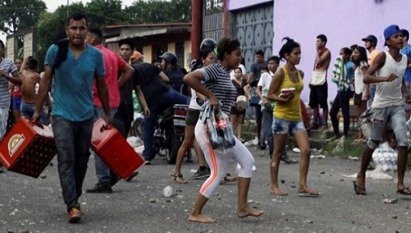 People carry goods taken in La Fria, Venezuela, Dec. 17, 2016.