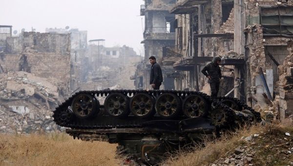 Pro-government forces stand atop a damaged tank near Umayyad mosque, in west Aleppo, during a media tour, Syria Dec. 13, 2016. 